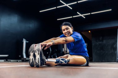 Protez bacaklı bir sporcu GYM üzerinde egzersiz yapıyor. Spor salonunda koşmak için protez ekipman takan bir kadın. Protez bacaklı bir kadın..