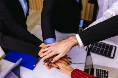 İnsanlar ellerini birleştiriyor. Birlik ve takım çalışması sergileyen el yığınları olan arkadaşlar. İş adamları toplantılarında el ele tutuşurlar. Takım çalışması konsepti. İş adamları el ele tutuşuyor.
