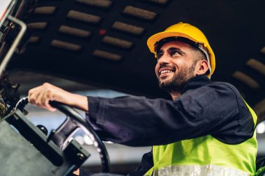 Forklift sürücüsünde çalışan adam fabrika lojistik gemisinde çalışmaktan mutlu. Depoda forklift şoförü var. Forklift sürücüsü depoda araçta oturuyor.