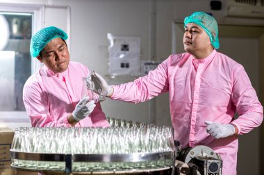 Worker Checking quality or checking stock of glass bottle in beverage factory. Worker QC working in a drink water factory 