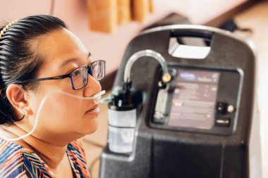 Hasta kadınlar solunumuna yardımcı olması için oksijen solunum cihazı takıyorlar. Hasta evde taşınabilir oksijen kullanıyor. Solunum bozuklukları olan hastalar. taşınabilir oksijen konsantratörü veya oksijen üreticisi