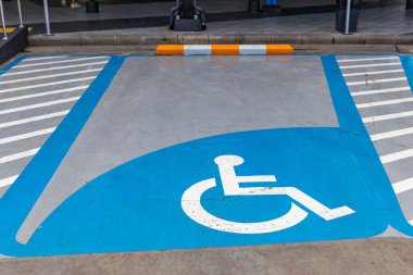 Engelli ya da tekerlekli sandalye park yeri. Park yerindeki engelliler için ayrılmış park yeri tabelası var. Uluslararası engelli sembolü bir alışveriş merkezinin park yerine açık maviyle boyanmış.. 