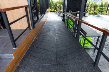 Binanın önünde engelli yolu var. Engelli trafik sembolü, destek tekerlekli sandalyesi için rampanın önünde. Yeşil doğa manzarasında kafenin önünde engelli bir yol.