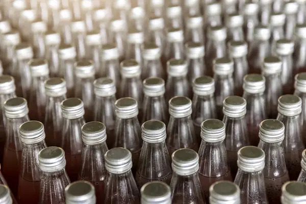 Juice in glass bottles in factory to fill with drink. Juice in glass bottles in a factory for the food industry, Row of bottling line for processing at beverages factory