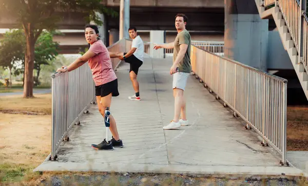 Arkadaş, dışarıda egzersiz yaparken protez bacaklı arkadaşına destek oluyor. İnsanlar parkta birlikte yürüyorlar. Yürüyüş egzersizi yapan protez bacaklı kadın ve arkadaşı parkta birlikte destek oluyor.