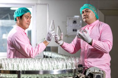 Worker Checking quality or checking stock of glass bottle in beverage factory. Worker QC working in a drink water factory 