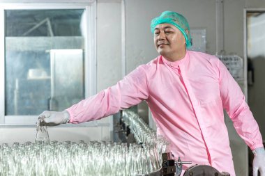 Worker Checking quality or checking stock of glass bottle in beverage factory. Worker QC working in a drink water factory 