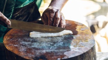 Mersin balığı deneyimli şefin elinde. Sashimi ve suşi için mersin balığı filetosu dilimlemek için bıçak kullanıyor. Bir şef kesme tahtasındaki bıçakla mersin balığı filetosu kesiyor..