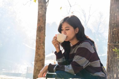 Woman drink coffee in morning time. young woman holding mugs while enjoying the view of nature.	