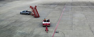 Terminalin yanındaki havaalanı önlüğündeki uçak çekici. Uçak Çekici Traktörü. Hava limanına ait çekici bir traktör subay tarafından kullanılıyor. Havaalanında traktör çekiliyor.