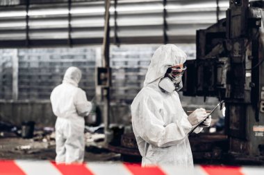 Kimyasal koruma giysisi giyen bilim adamları tehlikeli kimyasalları kontrol ediyor, kırmızı ve beyaz şeritli tehlikeli bölgelerde çalışıyorlar. Kırmızı ve beyaz Tehlikeli Bölge Fabrika Güvenlik İşçi Endüstrisi