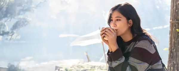 Woman drink coffee in morning time. young woman holding mugs while enjoying the view of nature. Woman traveler relaxing and drinking coffee with beautiful sunrise