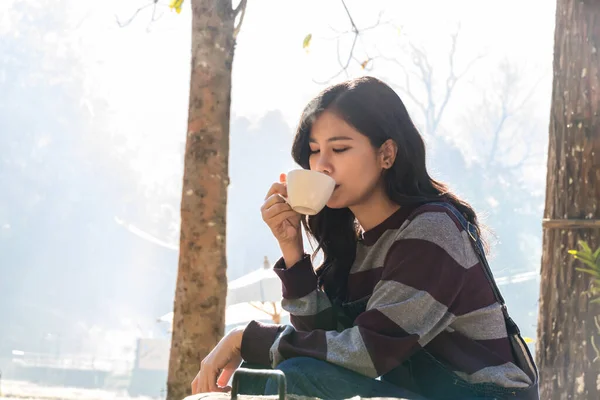 Woman drink coffee in morning time. young woman holding mugs while enjoying the view of nature.