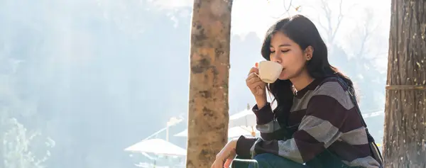 Woman drink coffee in morning time. young woman holding mugs while enjoying the view of nature. Woman traveler relaxing and drinking coffee with beautiful sunrise