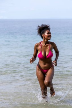 Yaz tatilinde kumsalda bir kadın. Tropik bir plajda güneşlenen güzel bir kız. Kumlu sahilde bikinili bir kadın turist. Cennetteki tropik plajda seksi bikinili kadın.