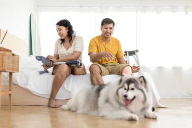 Evde köpek gibi otururken çiftler kaynaşıyor ve gülümsüyor. Evde köpekle yatakta oturan çift. Oturma odasında oturan protez bacaklı çift. Gündelik giyinen sevgili çift yatak odasında dinleniyor.