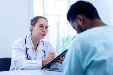 Doktor listeyi tutuyor ve hastanedeki hasta adamla konuşuyor. Doktor, erkek hastayı hastane odasında muayene ediyor..