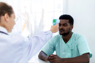 Doktor hastanın sıcaklığını hastane ya da klinikte ölçüyor. Ateşli Adam kişisi. Klinikte Doktor Sıcaklık Taraması ve Tıbbi Kontrol. 
