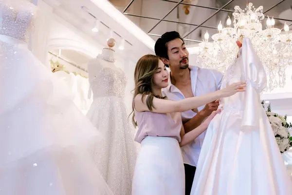 Bride and groom wear dress and try to fitting in wedding studio