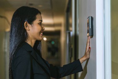 Ofis binasının kapısını açmak için yüz tarayıcı kullanan bir kadın. Yüz tanıma sistemine erişim. Güvenlik sistemi için biyometrik giriş kontrol cihazı. Biyometrik kabul kontrol aygıtı