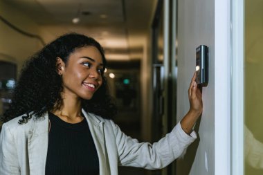 Ofis binasının kapısını açmak için yüz tarayıcı kullanan bir kadın. Yüz tanıma sistemine erişim. Güvenlik sistemi için biyometrik giriş kontrol cihazı. Biyometrik kabul kontrol aygıtı