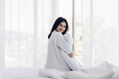 Uyandıktan sonra yatakta gerinen bir kadın. Gergin ve mutlu bir kadın uykusundan uyanır, dinlenir ve evde dinlenir..