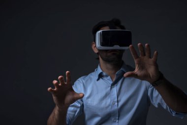VR kulaklıklı adam. İnternet oyunu için VR gözlük kullanan bir adam. Sanal gerçeklik kulaklığı kullanan yakışıklı bir adam. İnsan sanal gerçekliği VR kulaklığı ile tecrübe eder ve elleriyle bir şeye dokunur..