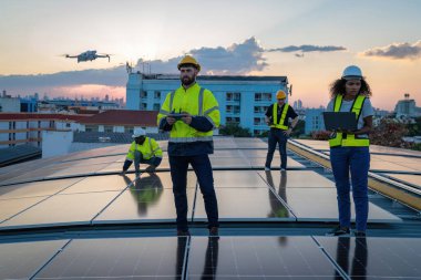 Ekolojik güneş çiftliğinde çalışan bir teknisyen. Yenilenebilir temiz enerji teknolojisi kavramı. Uzman mühendis kontrol İHA 'sı fabrikanın çatısına güneş paneli kurulumunun üst görüntüsünü kontrol ediyor 