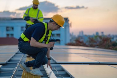 Fabrikanın çatısındaki güneş pilini kontrol et. Çatıda yürüyen mühendisler güneş pili panelini inceleyip kontrol ediyorlar. Çatıda çalışan mühendis teftiş kurulum güneş hücresi
