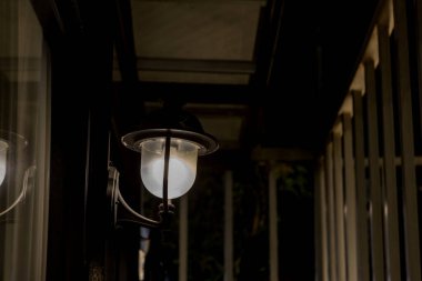 Duvardaki lamba ışığı. Duvarda eski tip demir fener var. Bir köyde bahçe metali elektrik lambası. Duvar lambası dışarıda..