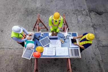 Ustabaşı ya da konteyner kargo alanında çalışan işçi. Mimari mühendis çalışıyor, toplantı yapıyor, plan yapıyor, güneş fotovoltaik ekipmanları ve rüzgar türbini ile plan yapıyor.