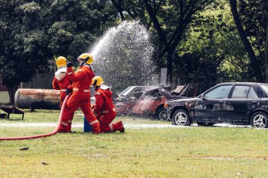 İtfaiyeci konsepti. Birkaç itfaiyeci bir yangın saldırısı için saldırıya geçiyor. İtfaiyeci ateş aleviyle savaşmak için su ve yangın söndürücü kullanıyor.. 