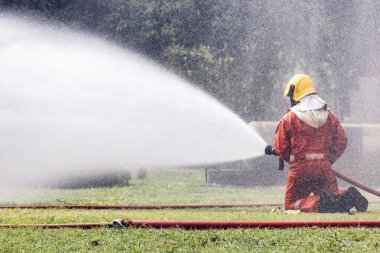 İtfaiyeci konsepti. Birkaç itfaiyeci bir yangın saldırısı için saldırıya geçiyor. İtfaiyeci ateş aleviyle savaşmak için su ve yangın söndürücü kullanıyor.. 