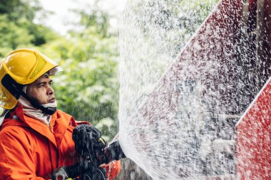 İtfaiyeci konsepti. Birkaç itfaiyeci bir yangın saldırısı için saldırıya geçiyor. İtfaiyeci ateş aleviyle savaşmak için su ve yangın söndürücü kullanıyor.. 