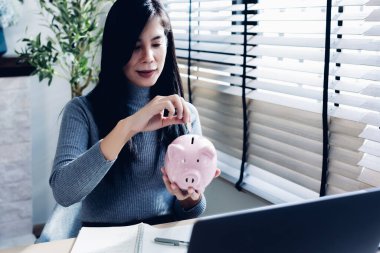 Kadın ev konseptinden çalışıyor. Muhasebe için para biriktiriyor. Tasarruf parası zenginlik kavramı, Asyalı iş kadını el yazısı yönetim bütçesi tasarruf maliyeti, nakit finans 