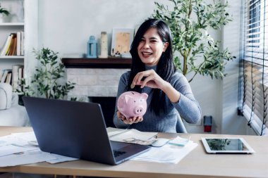 Kadın ev konseptinden çalışıyor. Muhasebe için para biriktiriyor. Tasarruf parası zenginlik kavramı, Asyalı iş kadını el yazısı yönetim bütçesi tasarruf maliyeti, nakit finans 