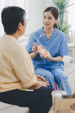 Diş hekimindeki kadın dişçi yaşlı kadın hastayla konuşuyor ve tedaviye hazırlanıyor. Diş cerrahisinde kıdemli bir kadınla konuşan bir dişçi..