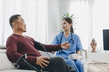 Caregiver nurse measuring blood pressure by using digital sphygmomanometer Senior patient at home. Caregiver nurse using medical device to measure blood pressure Senior patient.	