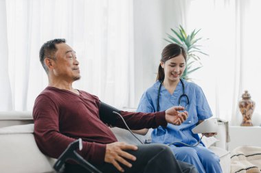 Caregiver nurse measuring blood pressure by using digital sphygmomanometer Senior patient at home. Caregiver nurse using medical device to measure blood pressure Senior patient.	