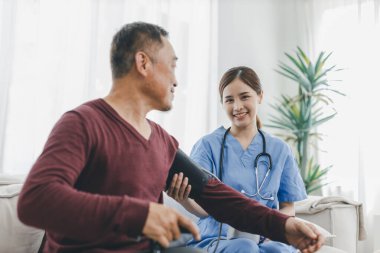 Caregiver nurse measuring blood pressure by using digital sphygmomanometer Senior patient at home. Caregiver nurse using medical device to measure blood pressure Senior patient.	