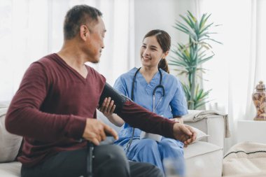 Caregiver nurse measuring blood pressure by using digital sphygmomanometer Senior patient at home. Caregiver nurse using medical device to measure blood pressure Senior patient.	