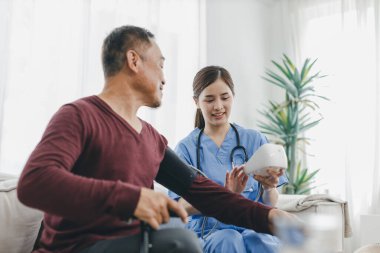 Caregiver nurse measuring blood pressure by using digital sphygmomanometer Senior patient at home. Caregiver nurse using medical device to measure blood pressure Senior patient.	