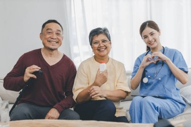 Hemşire eski hastasına bakımevinde yardım ediyor. Bakıcı, kıdemli hastaya kanepeye oturmasında yardım ediyor. Bakımevindeki hastalarla konuşan dost canlısı bayan hemşire.