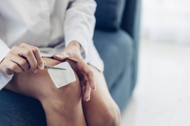 Kendi kendini iyileştiren kadın kazadan sonra ilk yardım yaralanması gerçekleştirir. Pamuk yumağı ve pansuman setiyle yaraları temizleyen kadın.