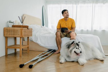 Evde, Livingroom 'da köpekli bir adam var. Evcil hayvan evde yaşarken bir ilham kaynağı oluyor. Sevimli hayvan. Köpek ve adam sahibi.