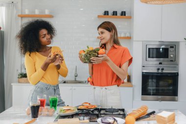 Sebze ve sosis, organik gıda ve GMO ürünleri arasında seçim yapan iki kadın. Mutfakta sağlıklı yiyecekler yemeyi seçen genç bir kadın abur cubur, şişman ve sağlıksız yemekleri karşılaştırıyor. 