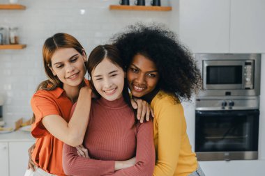 Mutfak odasında kucaklaşan çok ırklı lezbiyen çift. Yüzük tutan siyah beyaz bir çift. Afro-Amerikan ve beyaz lezbiyen çift birbirlerine şefkatle sarılıp bakıyorlar.
