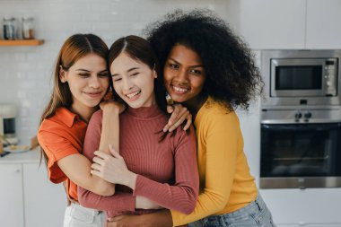 Mutfak odasında kucaklaşan çok ırklı lezbiyen çift. Yüzük tutan siyah beyaz bir çift. Afro-Amerikan ve beyaz lezbiyen çift birbirlerine şefkatle sarılıp bakıyorlar.