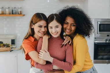 Mutfak odasında kucaklaşan çok ırklı lezbiyen çift. Yüzük tutan siyah beyaz bir çift. Afro-Amerikan ve beyaz lezbiyen çift birbirlerine şefkatle sarılıp bakıyorlar.