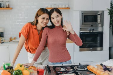 Mutfak odasında kucaklaşan çok ırklı lezbiyen çift. Yüzük tutan siyah beyaz bir çift. Afro-Amerikan ve beyaz lezbiyen çift birbirlerine şefkatle sarılıp bakıyorlar.